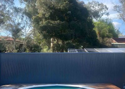 Above-ground pool with hardwood decking and a dark metal fence