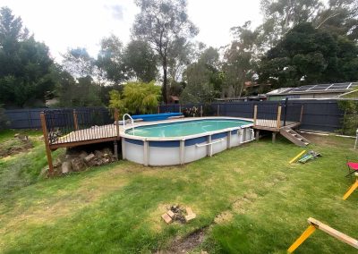 Above-ground pool in a grassy backyard with small decks at each end