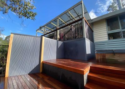 Hardwood deck steps with grey corrugated screens below a raised veranda
