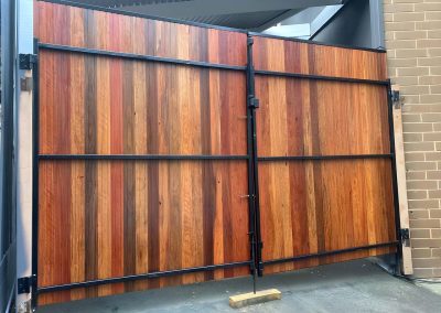 Back of stained hardwood double gates on a black steel frame