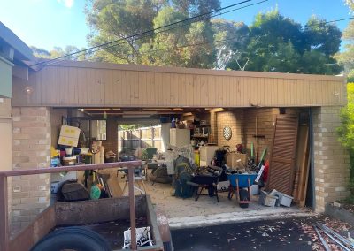 Open double garage full of stored items under a timber-lined fascia