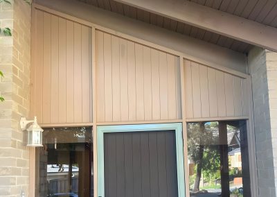 Gable entry with painted vertical board cladding above a grey front door
