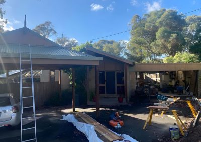 Carport under construction with a ladder and timber on the driveway