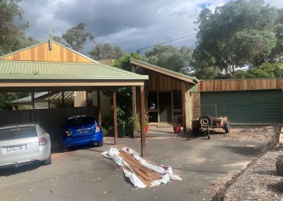 Gabled carport with a green metal roof and timber gable over two cars