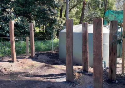 Timber posts set in the ground beside a water tank