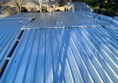 New corrugated metal roof sheets being laid on a house