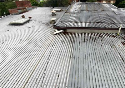 Old weathered corrugated metal roof with vents and a skylight