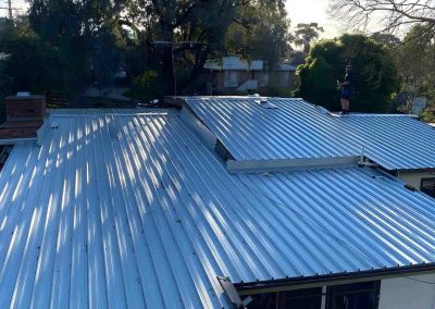 Finished new corrugated metal roof on a house among trees