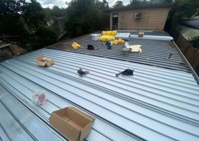 New metal roof sheets being laid with tools and boxes on the roof