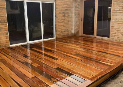 Freshly oiled hardwood deck in the corner of a brick house