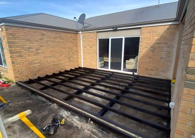 Black steel deck subframe in the corner of a brick house
