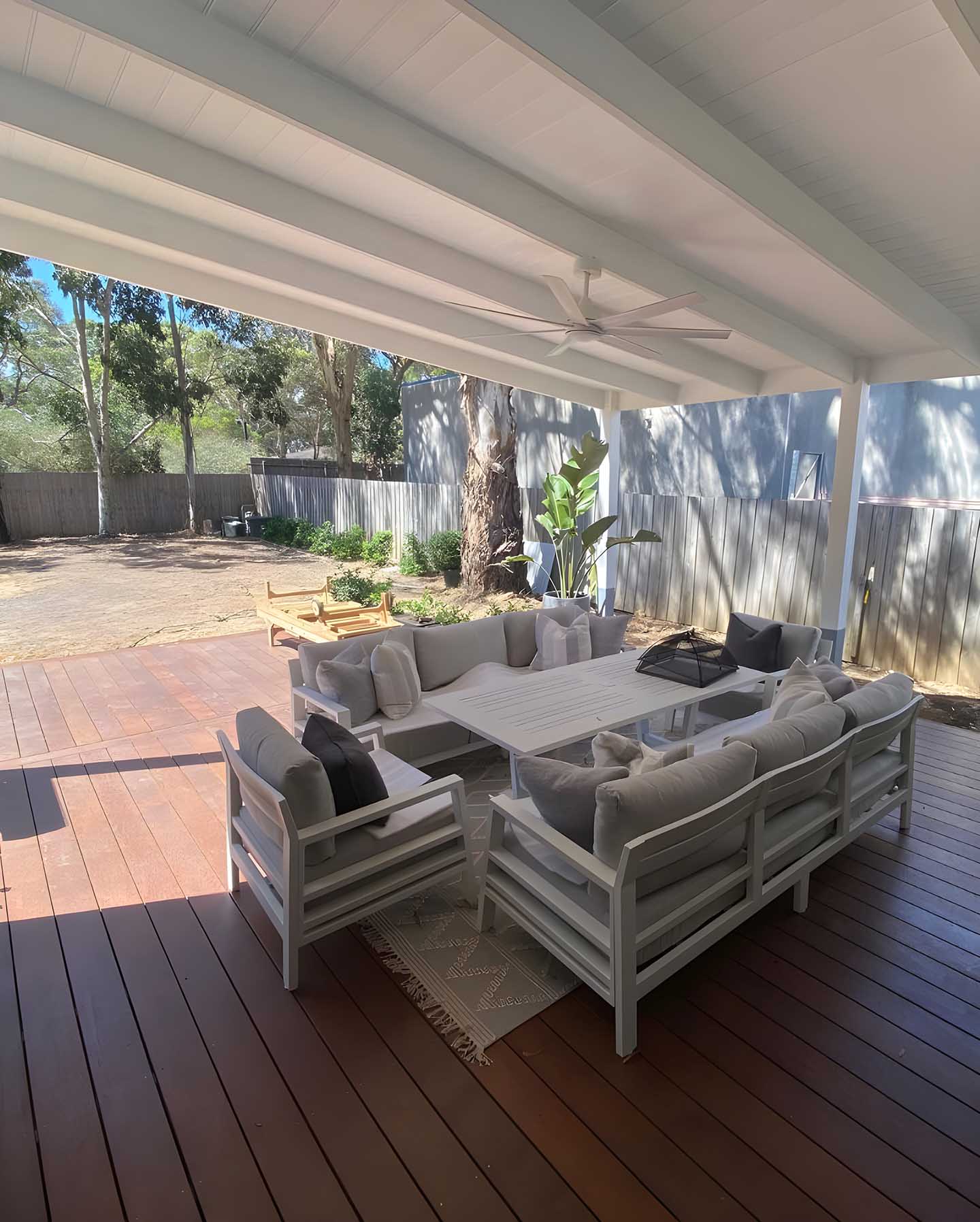 Covered timber deck with a white-lined roof and outdoor lounge furniture