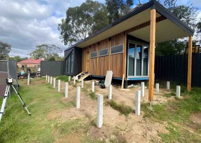 Concrete stumps set out in front of a timber-clad backyard studio