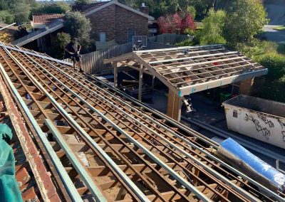 Roof stripped back to the timber battens beside a gabled pergola frame