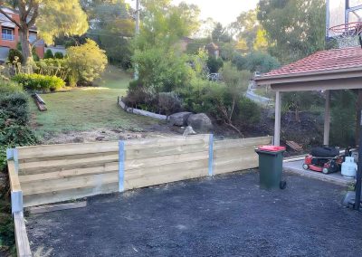 Treated pine sleeper retaining wall with steel posts beside a driveway
