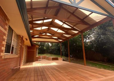 Finished hardwood deck under a gable pergola with clear roof panels