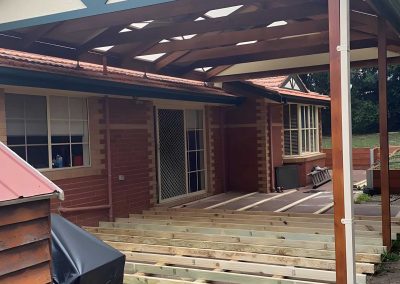 Treated pine deck frame being built under a gable pergola