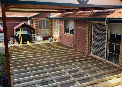 Treated pine deck subframe under a gable pergola beside a brick house