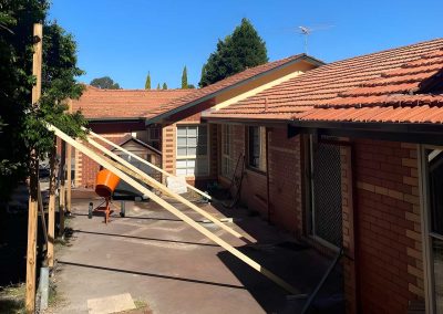 Timber posts and bracing going up beside a brick house