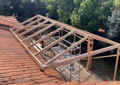 Gable pergola frame beside a terracotta tiled roof, seen from above