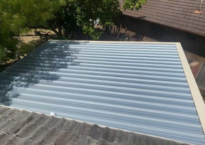 New corrugated metal roof sheets beside an older tiled roof