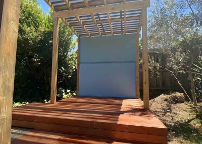 Small hardwood deck with steps under a timber slat pergola