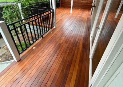 Freshly oiled hardwood deck with a black balustrade beside French doors