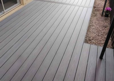 Grey composite decking along the side of a brick house