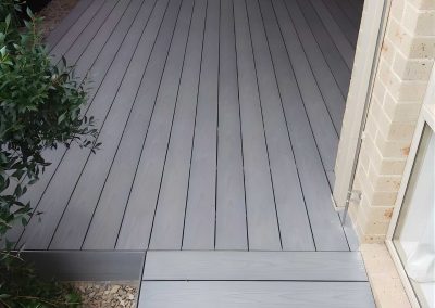 Grey composite decking and a step along a narrow side path