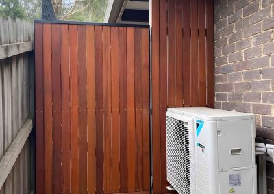 Stained timber gate and screen beside an air conditioning unit