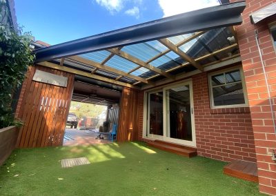 Clear-roofed pergola and timber slat screens over an artificial grass courtyard