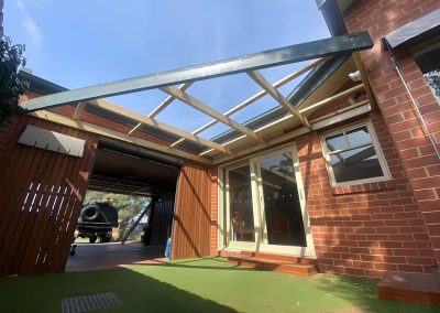 Pergola with clear roofing over a brick courtyard with artificial grass