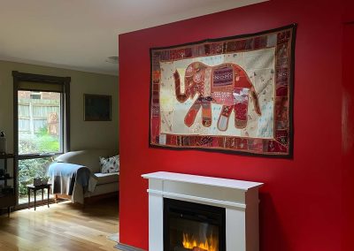 Living room with a red feature wall, electric fireplace and timber floor