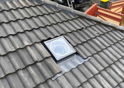 Skylight fitted into a grey tiled roof with flashing