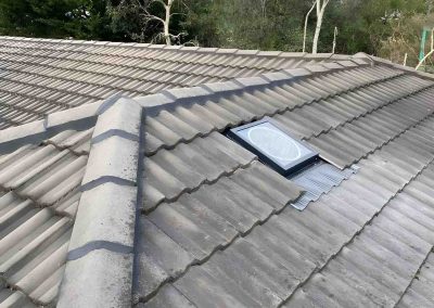 Skylight set into a tiled roof beside the ridge line