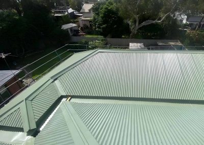 Finished green corrugated metal roof with hips and ridges