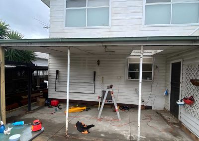 Rear patio of a weatherboard house with old veranda posts and tools