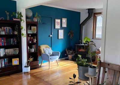 Wide new wall opening into a room with a teal feature wall and bookshelves