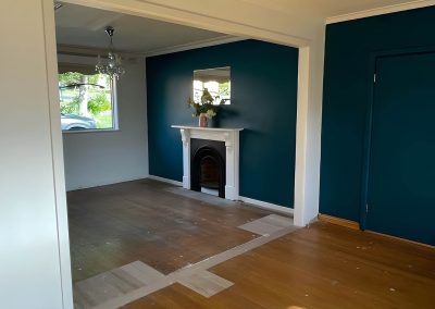 Empty room with a teal feature wall and fireplace through a wide opening