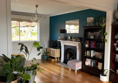 Furnished living room with a fireplace and teal wall through a wide opening