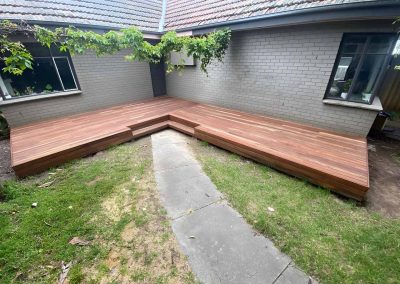 New L-shaped hardwood deck in a grey brick house courtyard
