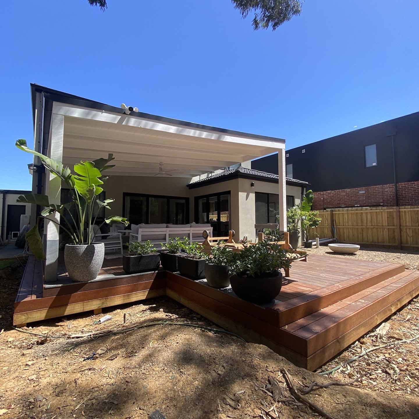 After: new multi-level timber deck with steps behind a modern house