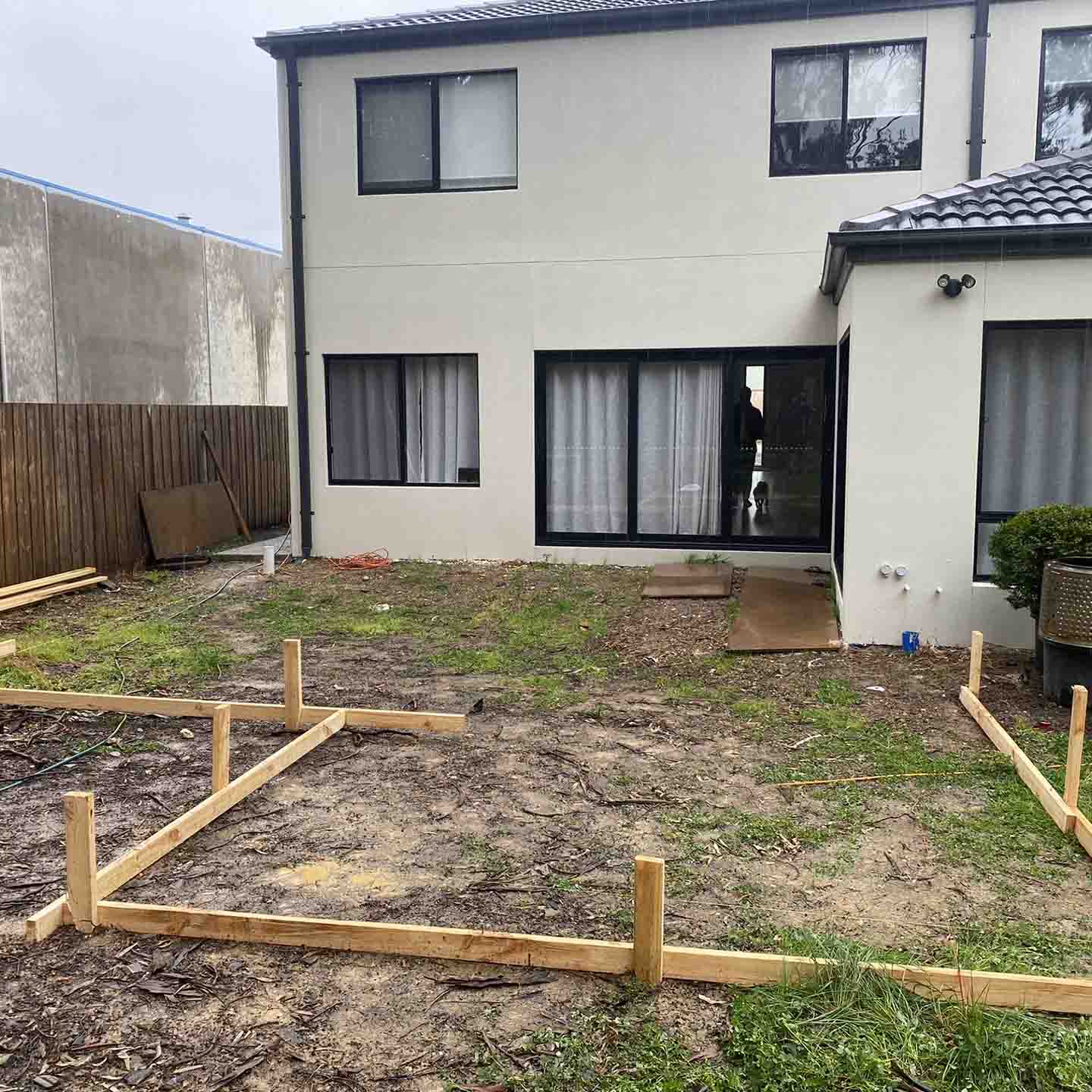 Before: bare backyard behind a two-storey house with timber set-out for a deck