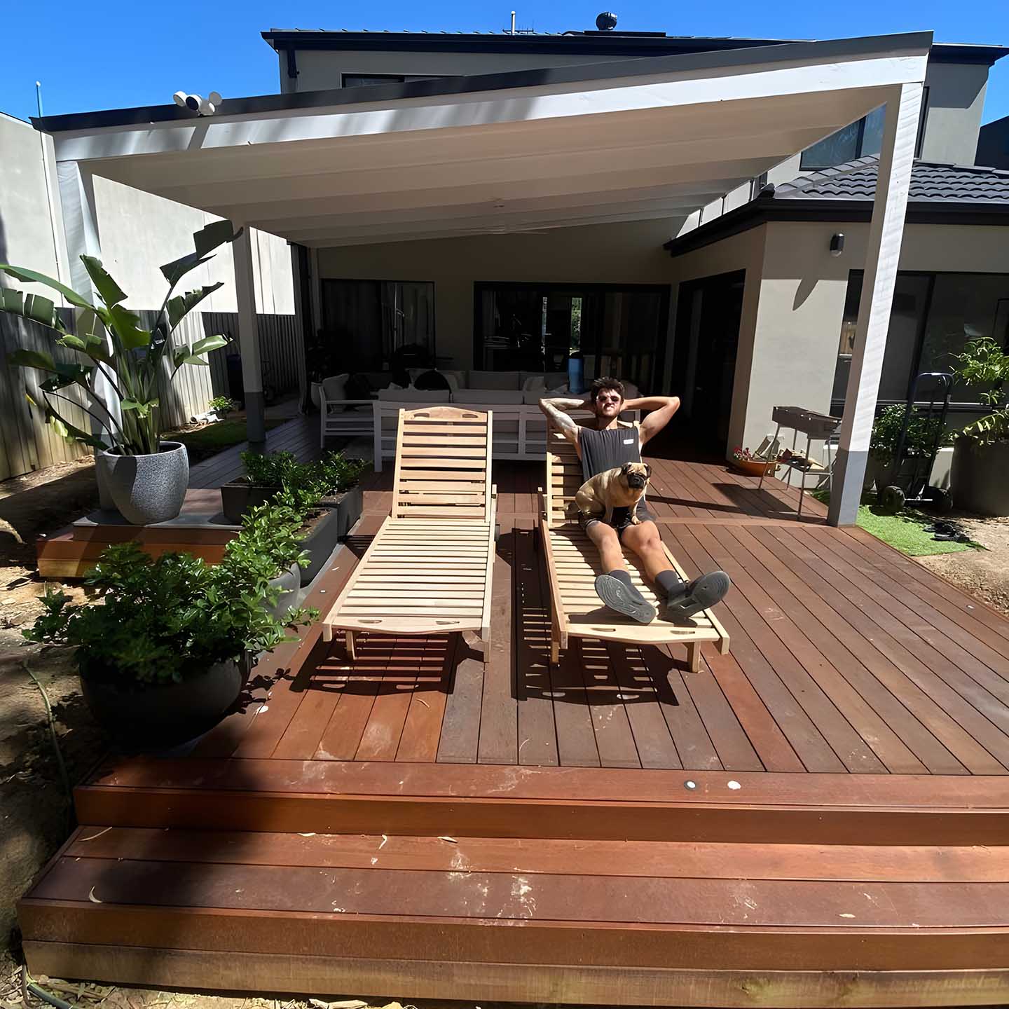 Person on a sun lounger on a large multi-level timber deck