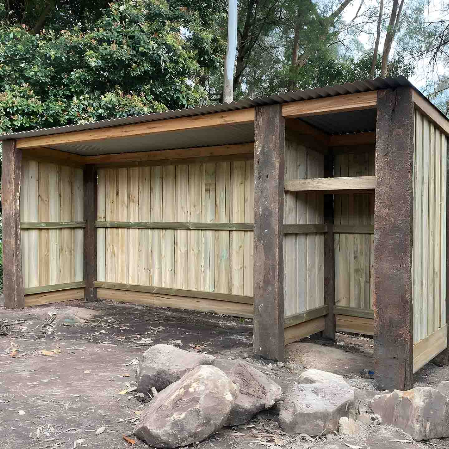 Woodshed with sleeper posts, paling walls and a metal roof
