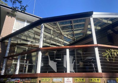 After: new pergola with clear roofing over a raised deck, wider view