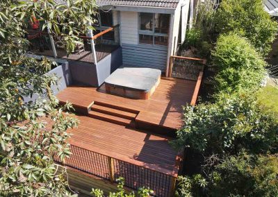 After: multi-level hardwood deck with steps and a spa below a house