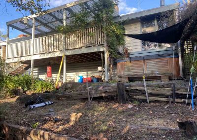 Before: sloping backyard with old timber sleepers below a raised veranda