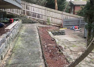 Before: narrow side yard with a concrete path and garden bed by a fence